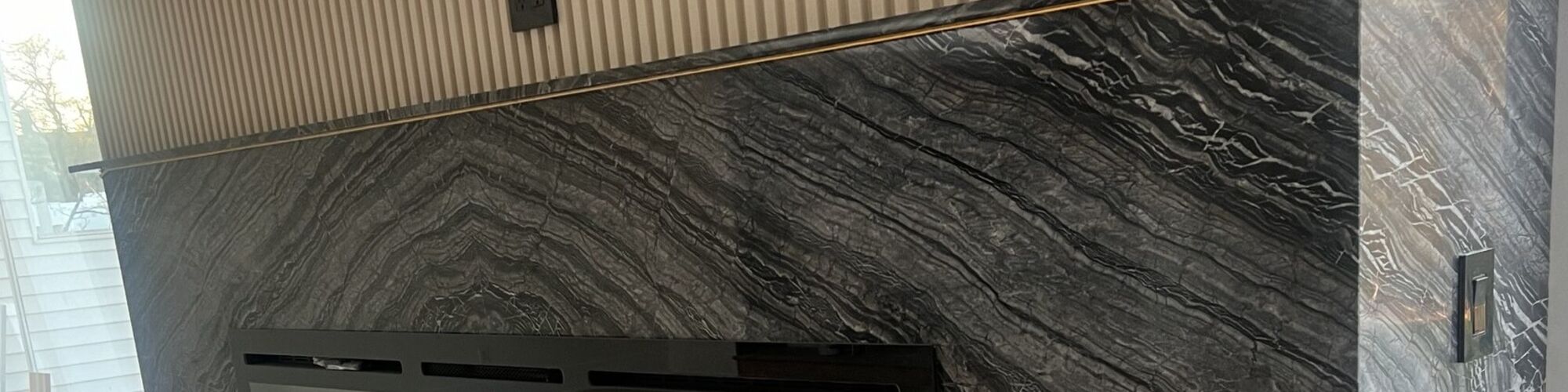 A stone feature wall wrapping a linear fireplace